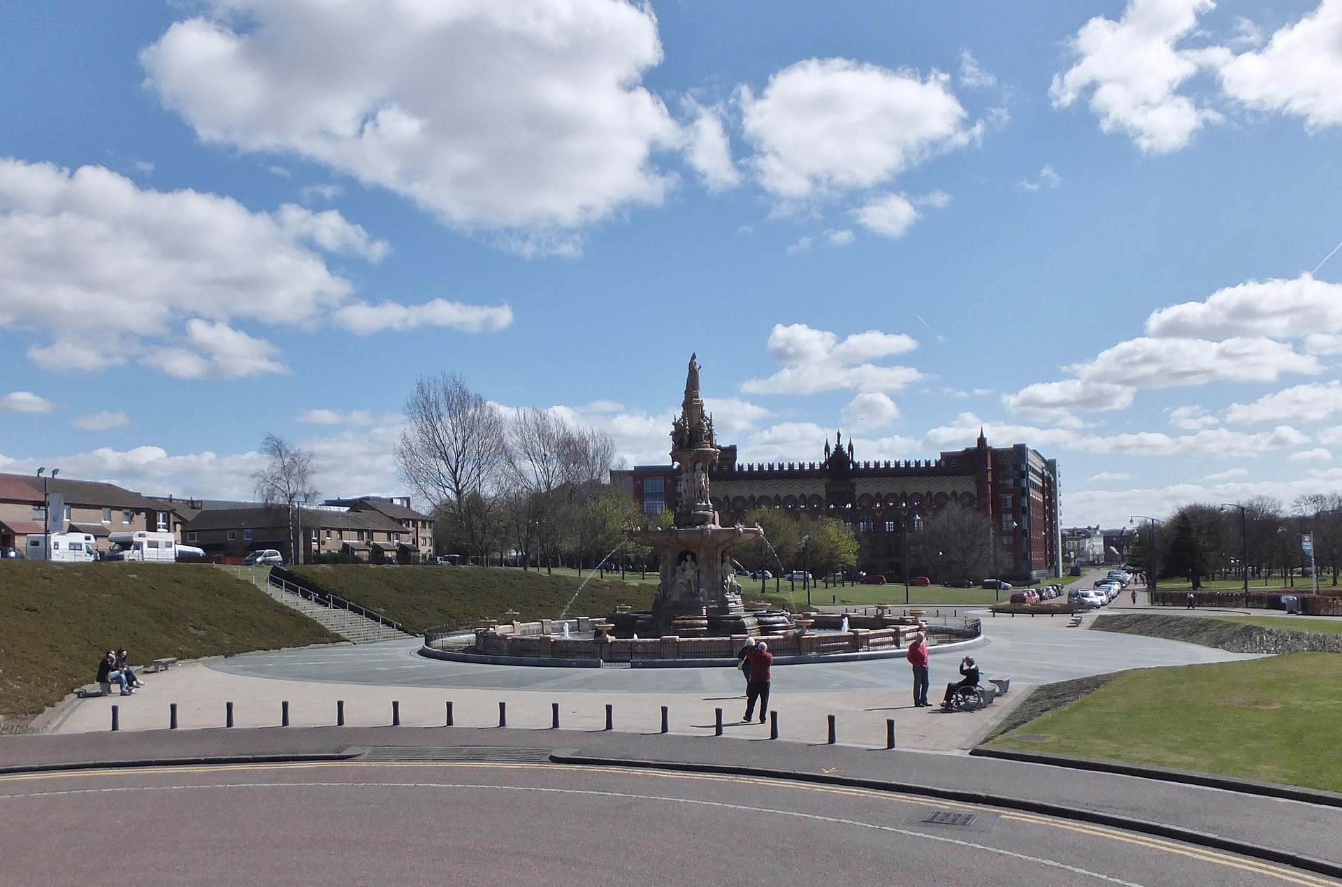 A sunny day on Glasgow Green, with people walking near the fountain