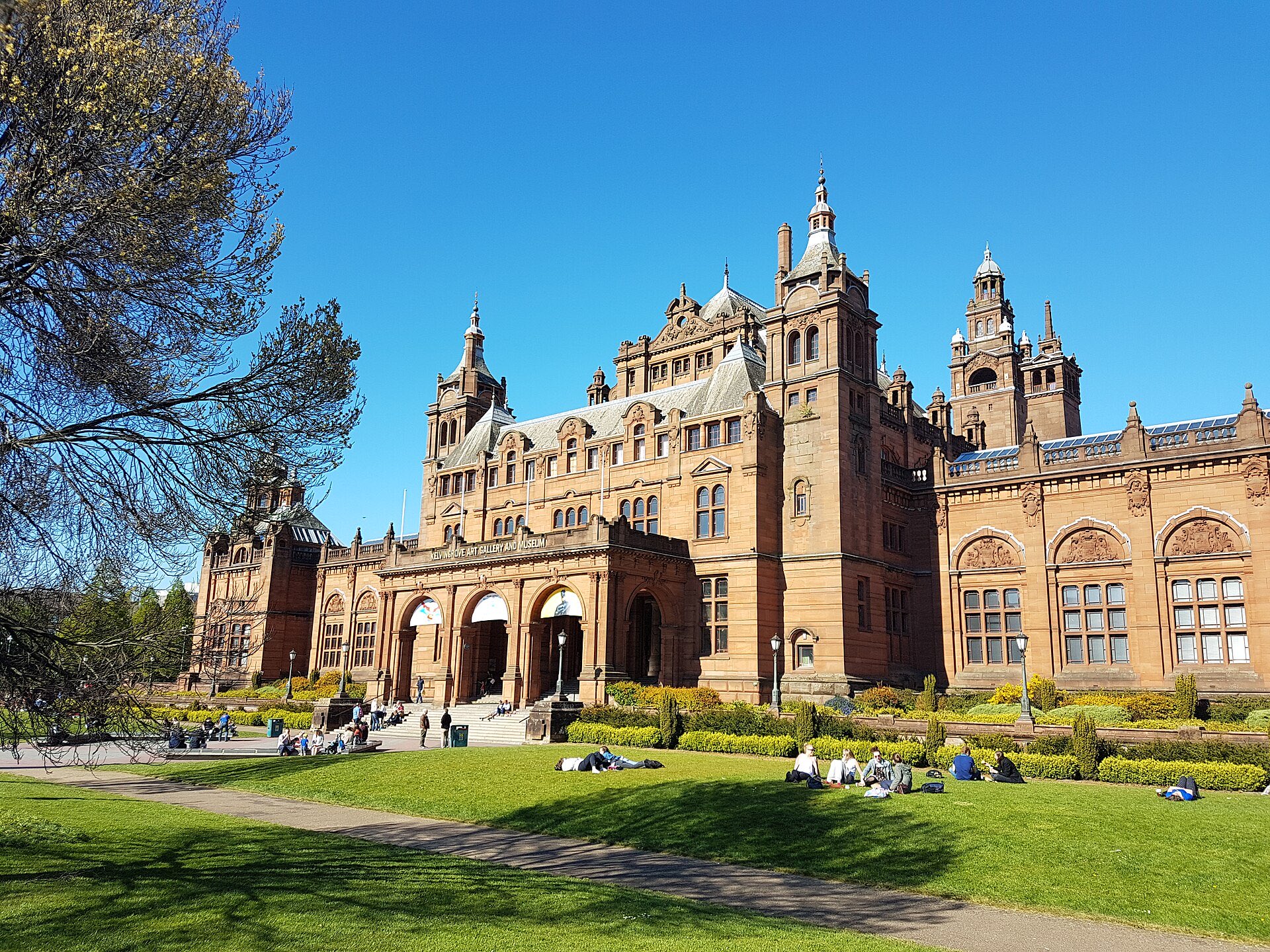 People relaxing on the lawn in front of Kelvingrove Art Gallery on a sunny day